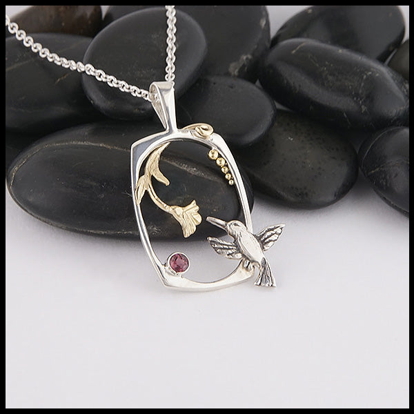 Custom Hummingbird pendant made in Sterling Silver and 14K Yellow Gold with a hummingbird, flower, and accent beads, set with a Rhodolite Garnet. 