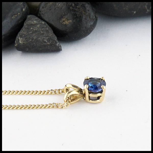 Profile view of 5mm Ceylon Blue Sapphire set in a 14K yellow gold setting with an 18" 14K Yellow Gold light curb chain.