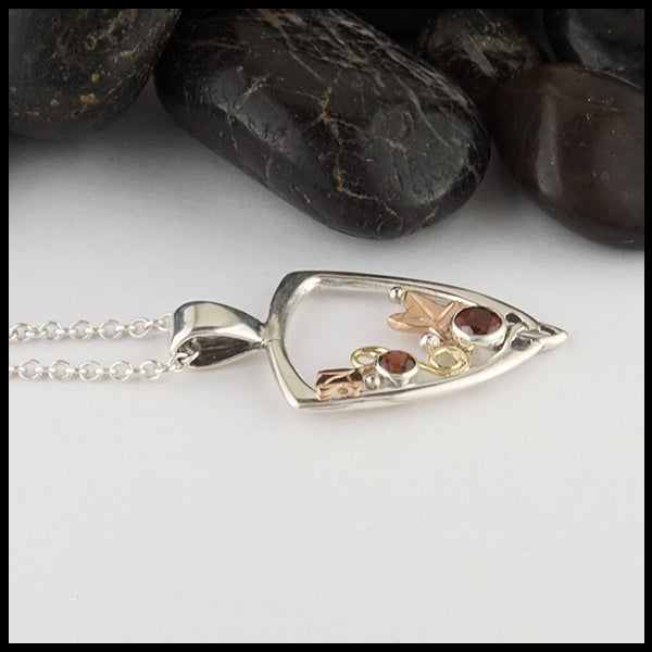 Profile view of Garnet Ivy Pendant in silver and gold