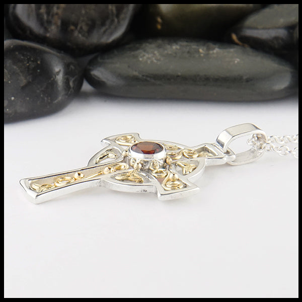 Profile view of garnet cross in silver and gold