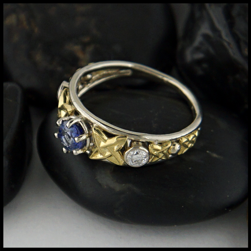 Custom Celtic ring with 14K White Gold frame and 18K Yellow Gold details. set with a Ceylon Sapphire and two 3mm Diamonds.
