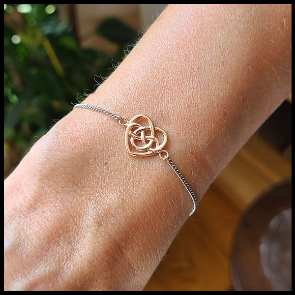 Robin's Heart bracelet features a 14K Rose gold heart on a 14K white gold chain. Shown on a wrist.
