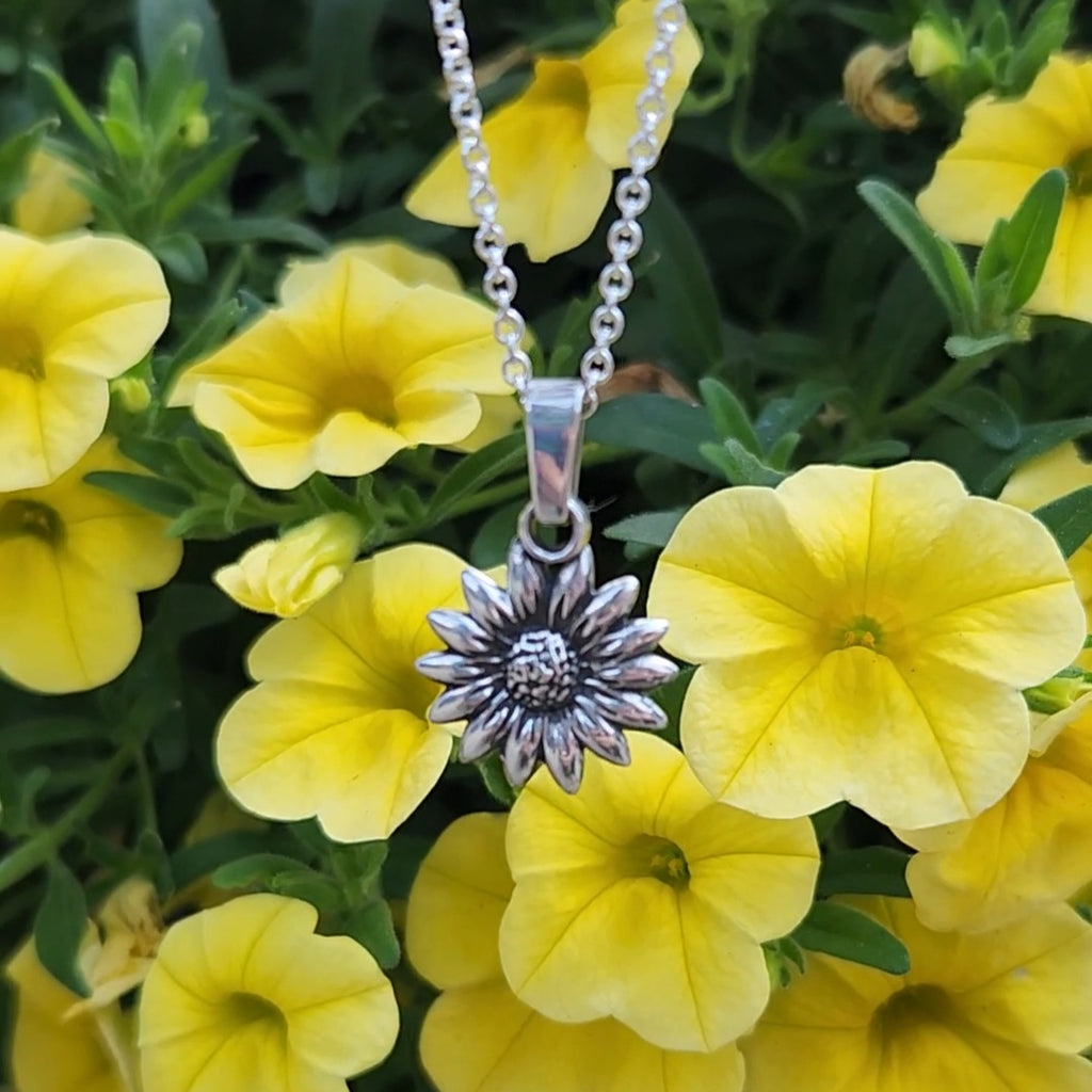 Silver sunflower pendant necklace among yellow flowers