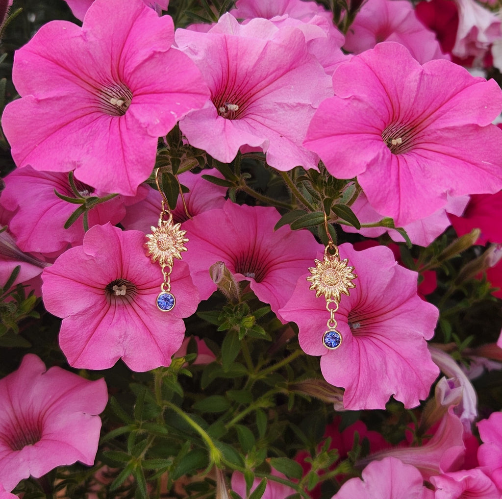 Surrounded by Pink Petunias, 14k Yellow Gold Sunflower Drop Earrings with Bright Tanzanites Dangling, Below Bezel Set in 14K Yellow Gold. Made by our craftsman Nicole