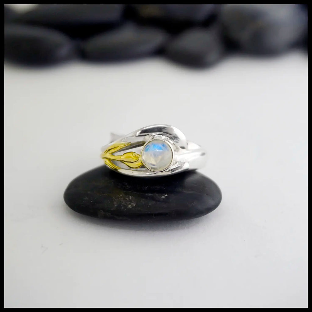 Silver ring with a moonstone and a Yellow Gold Tulip on a black stone against a white background