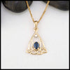 Gold pendant with a blue sapphire on a white background