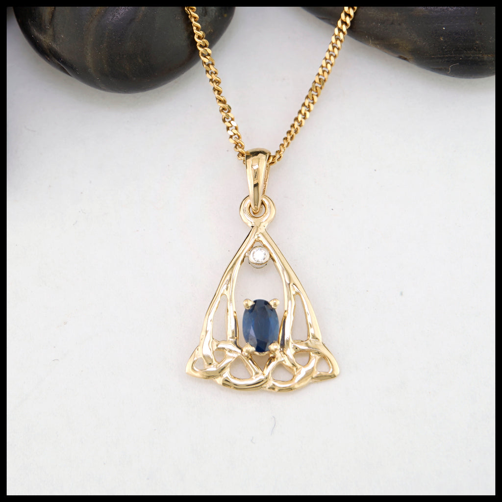 Gold pendant with a blue sapphire on a white background