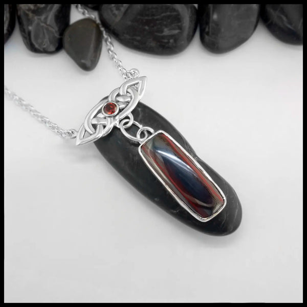 Rectangular Cabochon Red Tiger's Eye Sterling Silver pendant attached below a Sterling Silver Celtic Knot with a Dark Amber colored Citrine set in the center on a white background