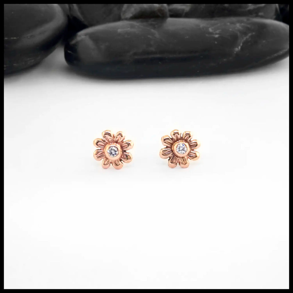 Rose gold flower-shaped earrings with a central Diamond on a white background