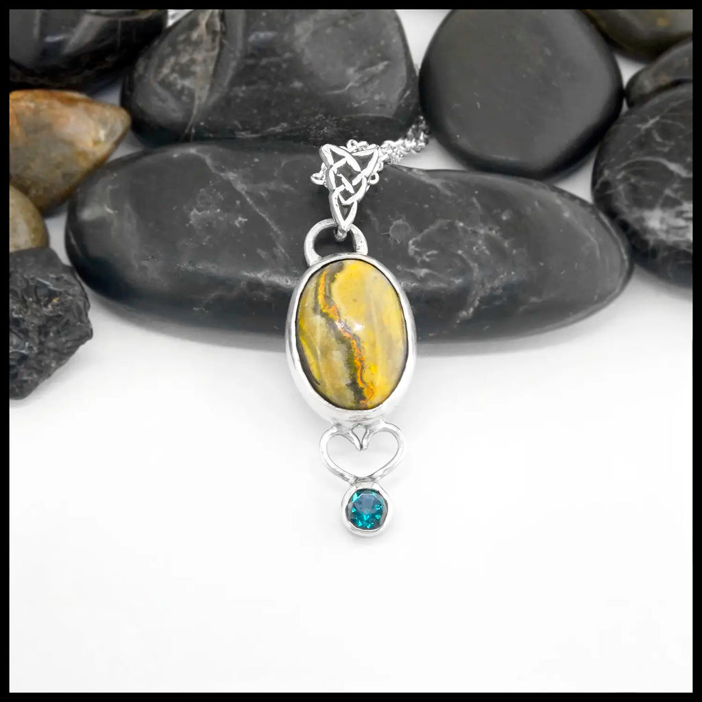 Silver pendant with yellow Bumblebee Jasper and evergreen Topaz on a white background. Custom Celtic knot Bale. includes an 18-inch cable chain. Made by Terry.