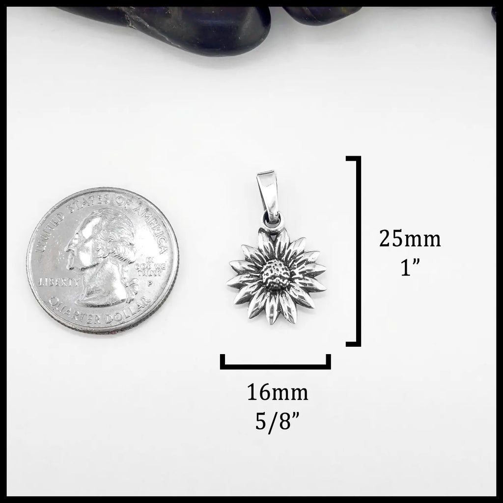 Silver sunflower pendant with size measurements relative to a quarter on a white background. Measurement: 25mm or 1" Tall and 16mm or 5/8" wide.