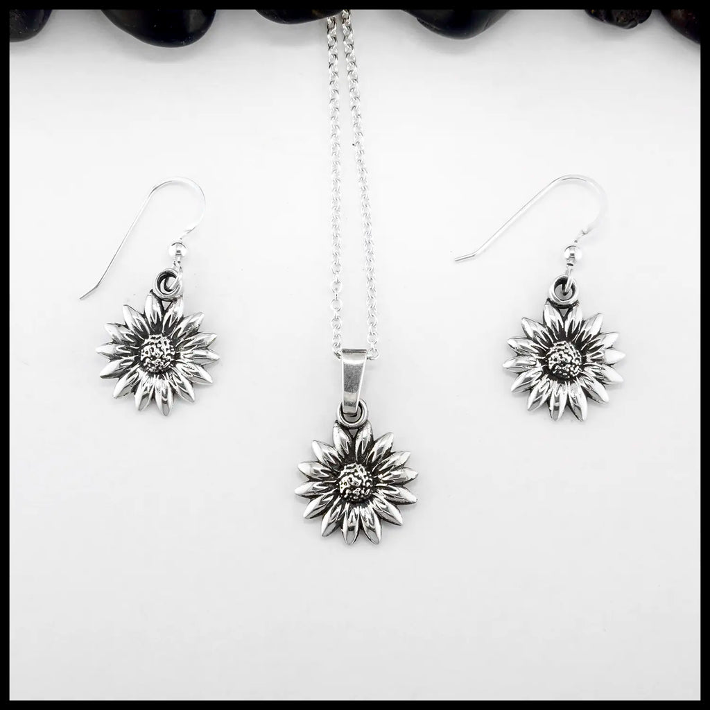 Silver sunflower pendant necklace and earrings on a white background