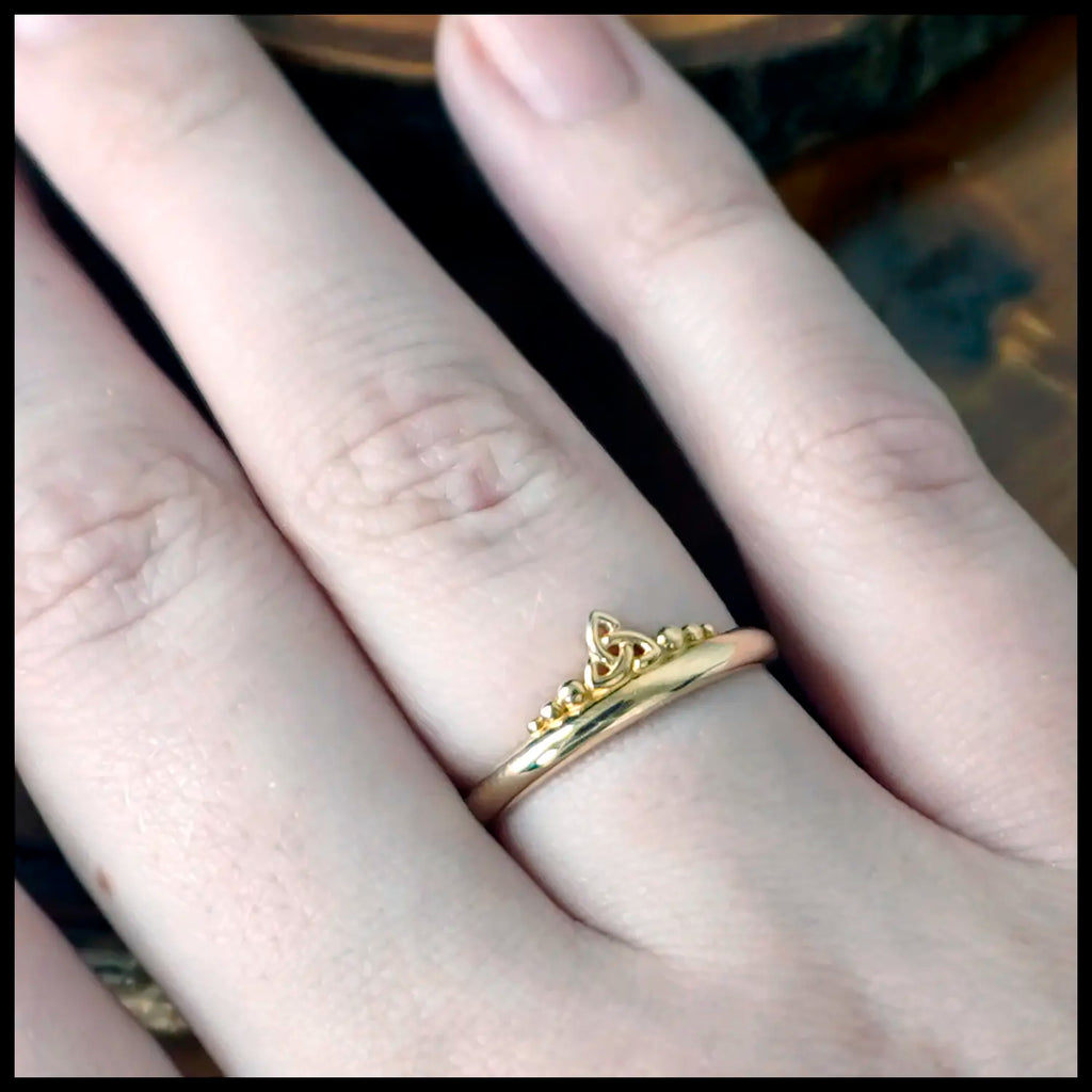 Gold Trinity Knot ring on a finger with a blurred background
