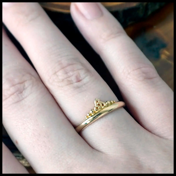 Gold ring with a trinity knot and beading design on dark stones