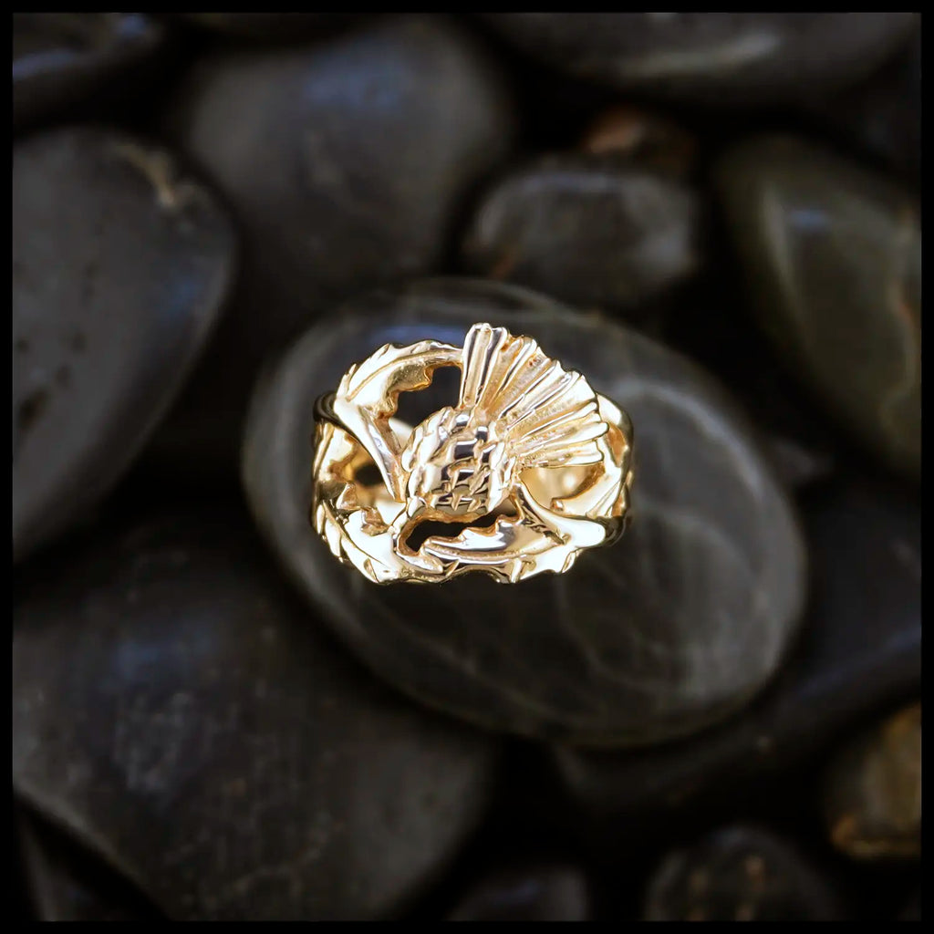 14K Yellow Gold ring with a detailed Scottish Thistle design on a dark stone surface