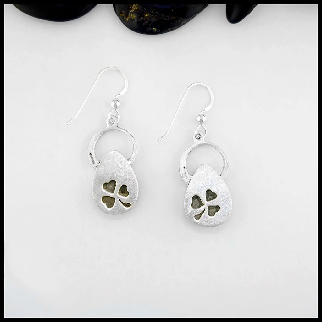 Silver drop earrings with clover designs on a white background