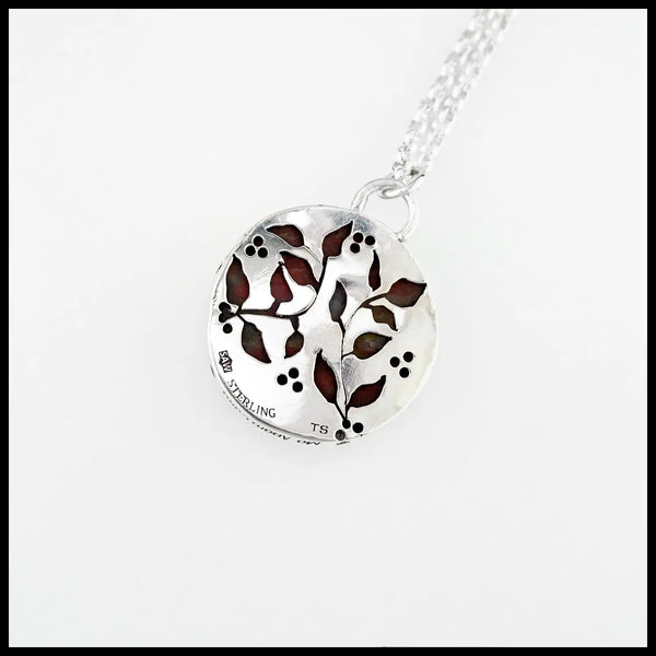 Silver pendant backing with leaf and vine cutouts, revealing the bloodstone through the openings