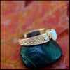 Rose gold ring with a opal stone on a black stone with a leafy background