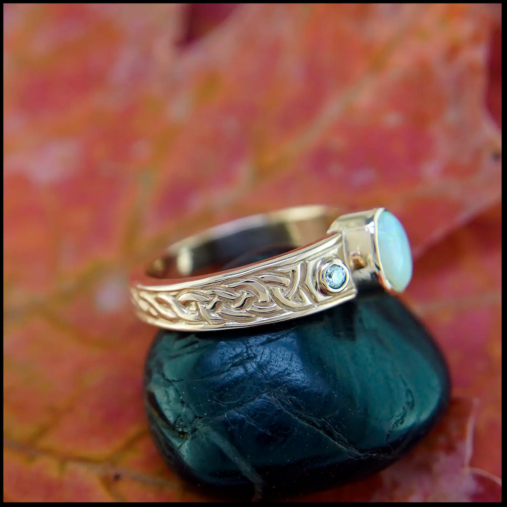 Rose gold ring with a opal stone on a black stone with a leafy background
