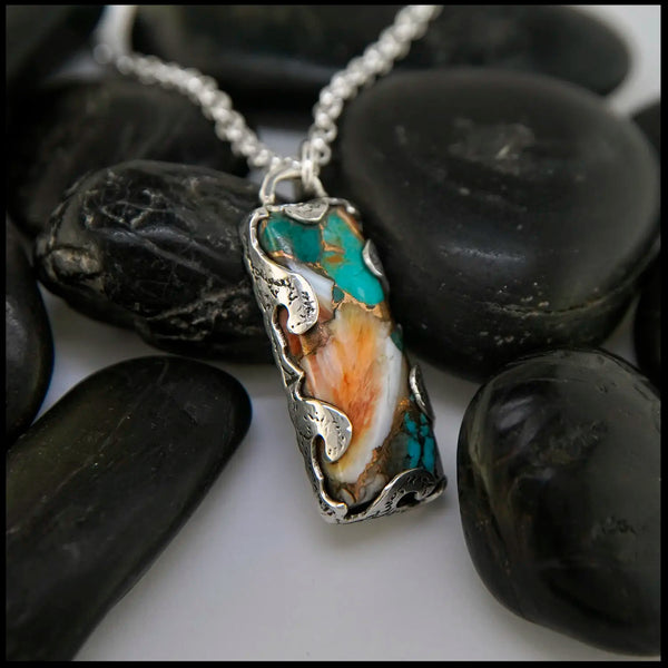 Necklace with a pendant featuring turquoise and orange stone on black stones