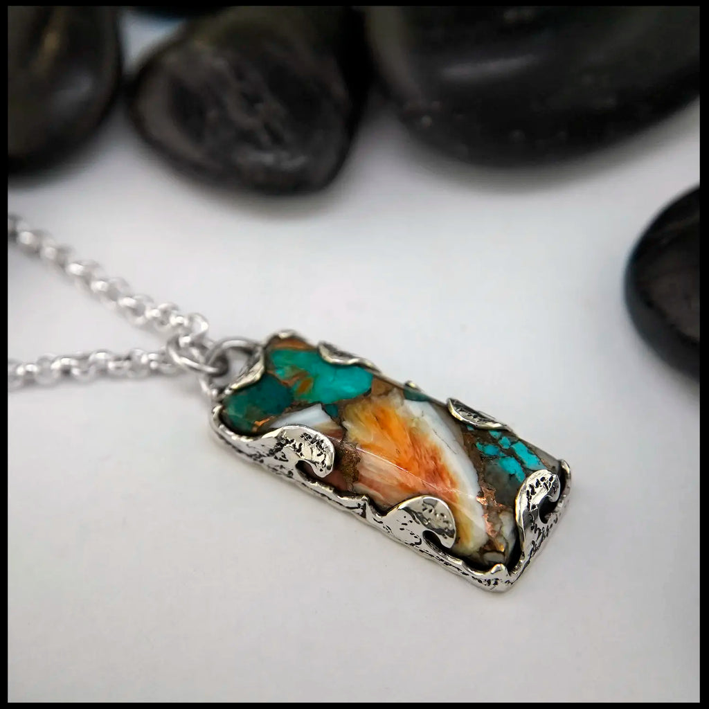 Necklace with a rectangular pendant featuring turquoise and orange colors on a white background.