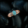 Rose gold ring with an opal and two diamonds on a dark background