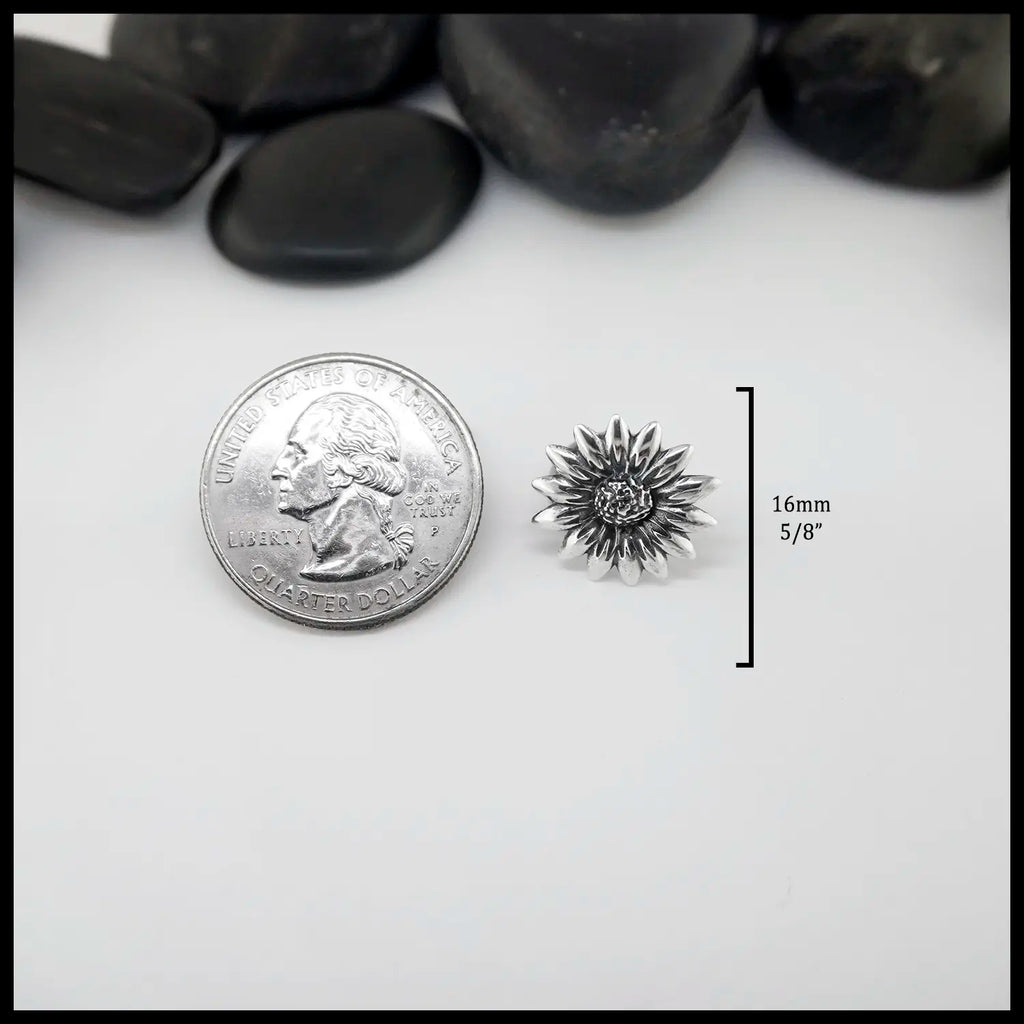 Silver flower-shaped Sterling Silver Pin on a white surface with black stones in the background. Measurements are 16mm or 5/8" circumference. 