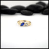 Gold ring with a Marquise Sapphire and a pear cut diamond on a white background