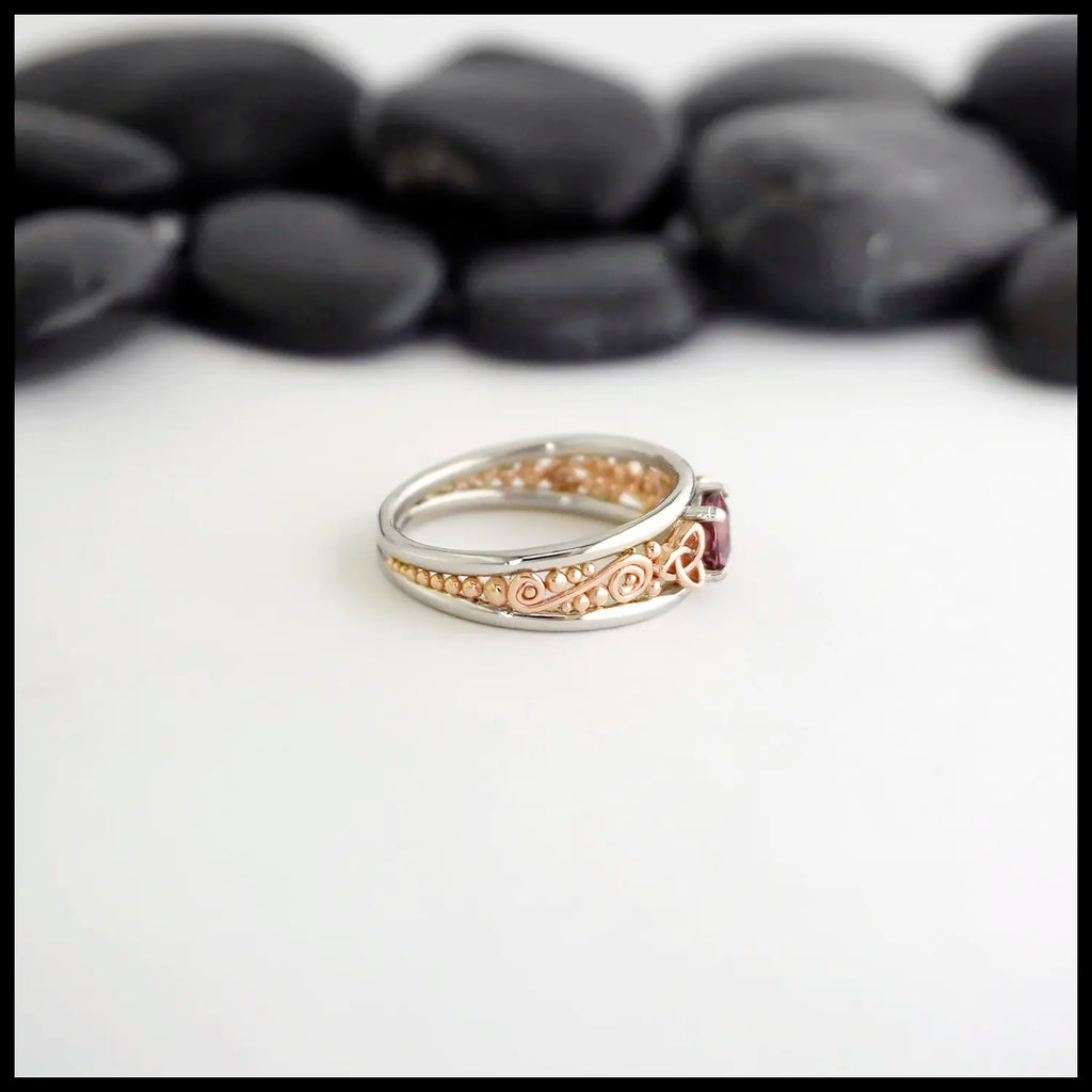 Side Profile 14K Rose Gold frame ring with 14K White Gold Rails,Set with a malaya garnet on a white background