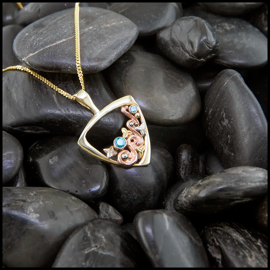 Gold Celtic swirl pendant with rose, white and yellow gold accents, set with a 3mm Tsavorite, and a 2mm Mint Garnet
