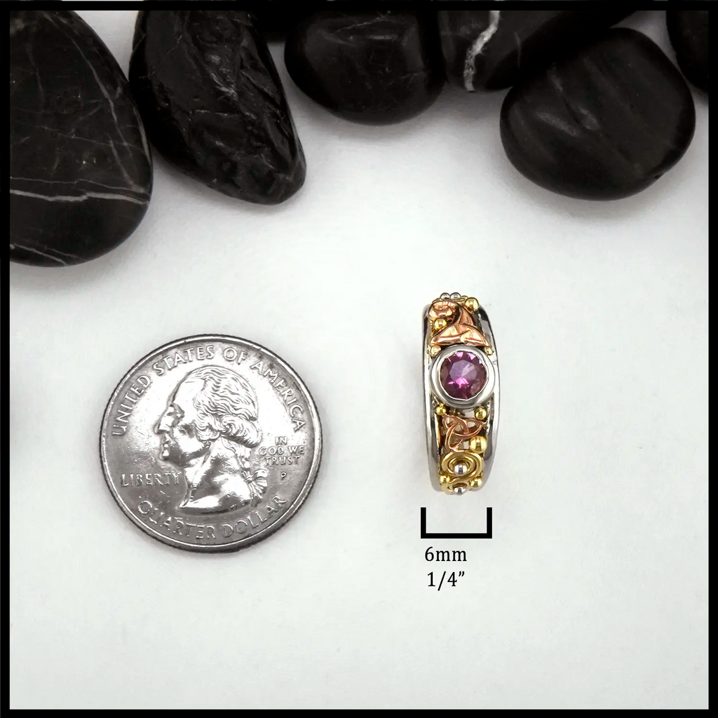 Gold ring with a purple gemstone next to a quarter for scale on a white background. 6mm wide
