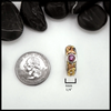 Gold ring with a purple gemstone next to a quarter for scale on a white background. 6mm wide