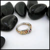 Multicolored ring with gemstone on a white surface with black stones in the background