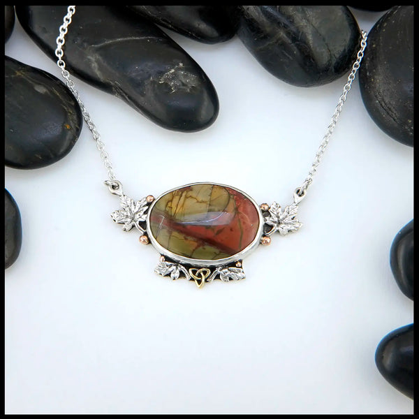 Red Creek Jasper set in Sterling Silver! surrounding the bezel are Sterling Silver maple leaves, 14K Rose Gold beads, and an 18K Yellow Gold Trinity.