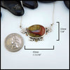 Necklace with a large oval pendant next to a coin for scale on a white background. 22mm by 43mm