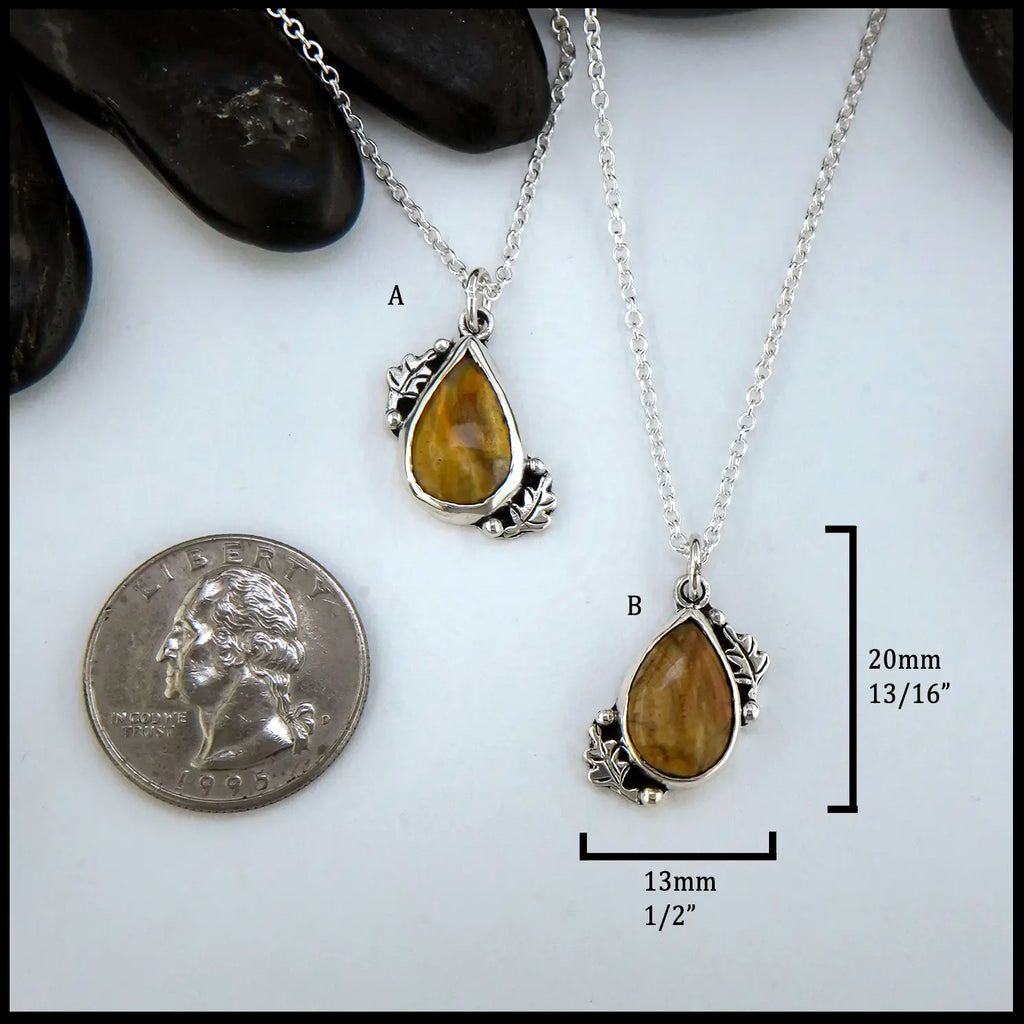 Petrified wood teardrop cabochon set in sterling silver with leaves next to quarter for scale.  20mm by 13mm