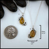 Petrified wood teardrop cabochon set in sterling silver with leaves next to quarter for scale.  20mm by 13mm
