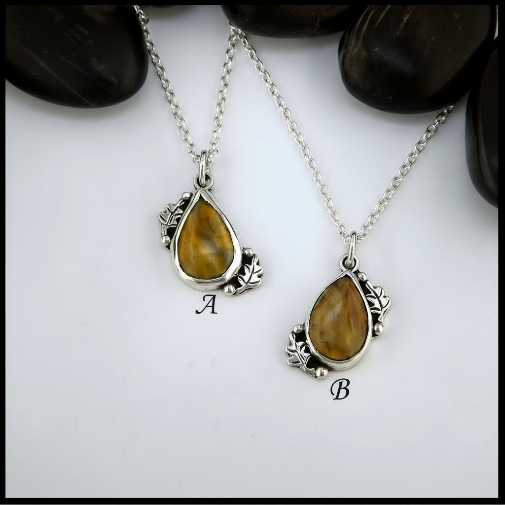 Two silver pendants with teardrop-shaped gemstones on a white background