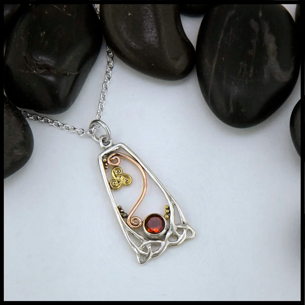Silver and gold pendant with a citrine gemstone on a white background