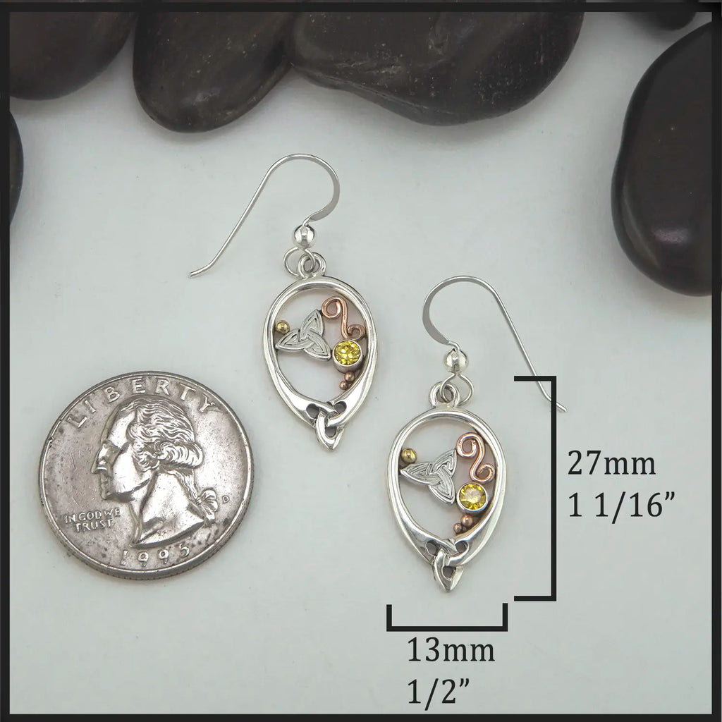 Silver earrings with gemstones on a white surface with a quarter for scale.