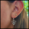 Close-up of an ear wearing a sterling silver triangle frame earring with a daisy design.
