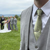 Celtic knot tie bar worn at a wedding, with the bride and groom in the background