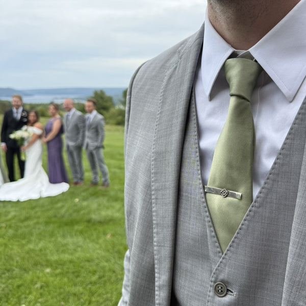 Celtic knot tie bar worn at a wedding, with the bride and groom in the background