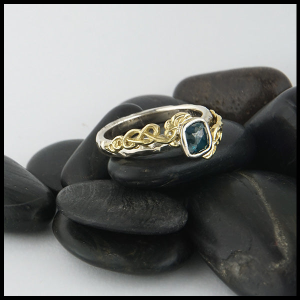 Custom 14K White Gold textured band with an 18K Yellow Gold cathedral design, set with a .59CT blue rose cut Diamond and a .06CT accent Diamond. 