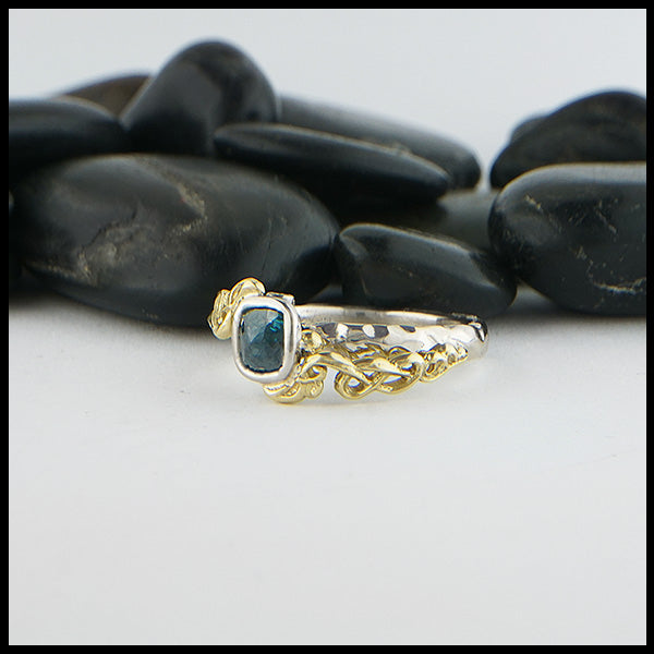 Profile view of 14K White Gold textured band with an 18K Yellow Gold cathedral design, set with a .59CT blue rose cut Diamond and a .06CT accent Diamond. 