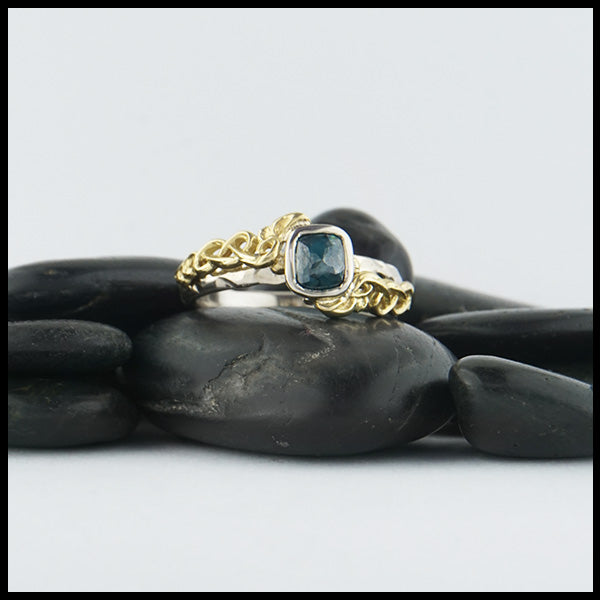 Custom 14K White Gold textured band with an 18K Yellow Gold cathedral design, set with a .59CT blue rose cut Diamond and a .06CT accent Diamond. 