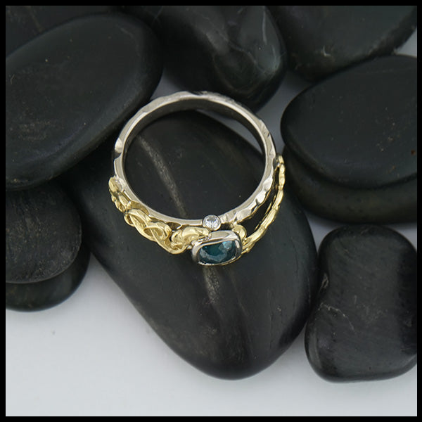 Band setting of custom 14K White Gold textured band with an 18K Yellow Gold cathedral design, set with a .59CT blue rose cut Diamond and a .06CT accent Diamond. 