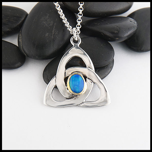 This sterling silver trinity knot features a black opal doublet set in a custom 14K yellow gold bezel. 