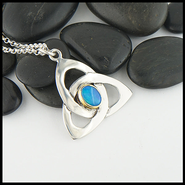 This sterling silver trinity knot features a black opal doublet set in a custom 14K yellow gold bezel. 