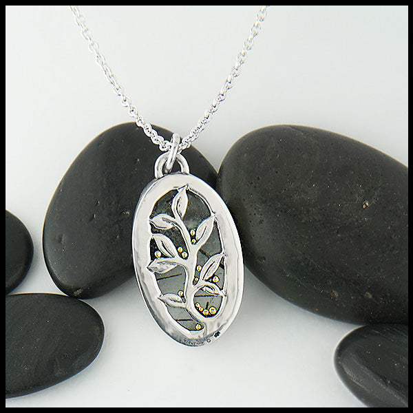 View of pendant from behind with custom hand-pierced vine design with 18K yellow gold details. Design is visible through the stone.